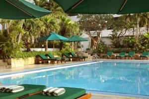 a swimming pool with green chairs and umbrellas at Aryaduta Menteng in Jakarta