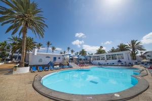 una gran piscina con palmeras y un edificio en Apartamentos Jable Bermudas, en Puerto del Carmen