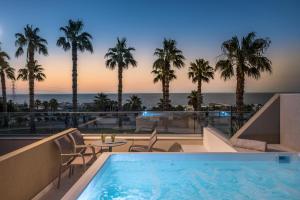 - une vue sur l'océan depuis la piscine de l'hôtel entourée de palmiers dans l'établissement Royal & Imperial Belvedere Resort, à Chersónissos