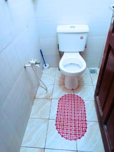 - une salle de bains pourvue de toilettes et d'un tapis rouge au sol dans l'établissement Bamburi Luxury Homes 2, à Bamburi