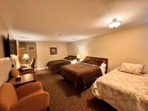 una habitación de hotel con 2 camas y una silla en Fundy Line Motel, en Miramichi