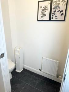 a bathroom with a toilet and two pictures on the wall at Amity Luxury Home Dartford in Kent
