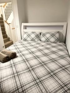 a bed with a plaid blanket and pillows on it at Amity Luxury Home Dartford in Kent