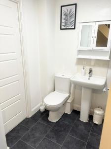 a bathroom with a white toilet and a sink at Amity Luxury Home Dartford in Kent