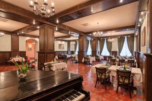 a restaurant with a piano in a room with tables at Hotel Traube in Mediaş