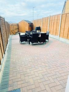 a patio with chairs and a table and a grill at Amity Luxury Home Dartford in Kent