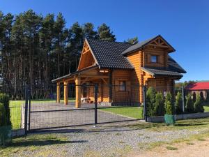 una cabaña de madera con una valla delante en Dom Wakacyjny z bali 'Złoto Północy', en Karwieńskie Błoto Pierwsze