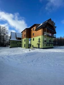 a large building in the snow with snow covered ground at Apartmán Sirius in Štôla