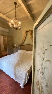 een slaapkamer met een groot wit bed en een kroonluchter bij Casa Bartoli - Panoramic House Buggiano Castello in Borgo a Buggiano