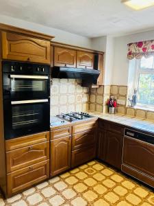 a kitchen with wooden cabinets and a stove top oven at Unwind in comfort at cosy Caradus your 8 bed Home Sweet Home! in Birmingham