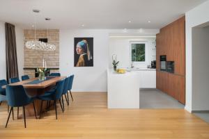 a kitchen and dining room with a table and blue chairs at Villa Roca with heated pool and sauna in Privlaka