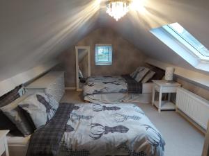 a attic room with two beds and a window at Ensuite room The bungalow William Harvey hospital in Willesborough