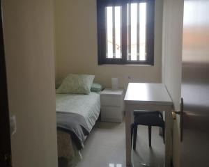 a bedroom with a bed and a desk and a window at Céntrico apartamento en Corrubedo in Corrubedo