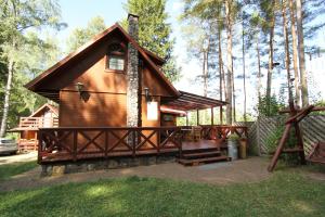 een hut in het bos met een veranda en een hek bij Dom nad jeziorem Dadaj BISKUPIEC in Wilimy