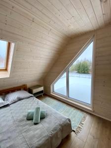 ein großes Schlafzimmer mit einem Bett und einem großen Fenster in der Unterkunft Mielno Woodhouse in Mielno