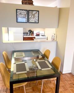 a glass table with yellow chairs and a kitchen at Gorgeous 2 Bedroom apartment in NYC! in New York