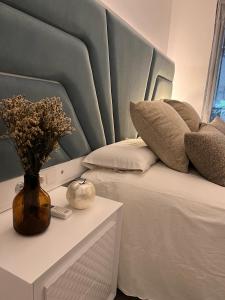 a bed with a blue headboard and a vase with flowers at Apartamento Mi Capricho in Sitio de Calahonda