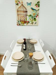 a white table with plates and glasses and a bird cage at Apartamento Meraki in Santa Cruz de Tenerife