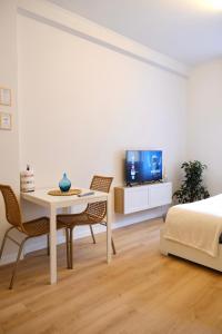 1 dormitorio con mesa, sillas y TV en Politecnico Bovisa university apartment en Milán