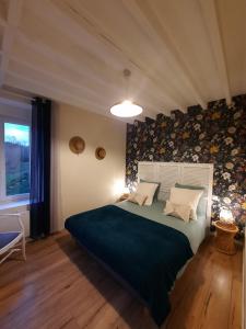 - une chambre avec un grand lit et une couverture bleue dans l'établissement GITE CHEZ BERTHE, à Pontfarcy