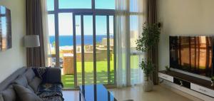 a living room with a couch and a large window at Apartment Azzura Sahl Hasheesh with private garden in Hurghada