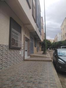 un edificio con un coche estacionado al lado de una calle en Appartement du lux très propre bien équipé au cœur de la ville nouvelle, en Meknès