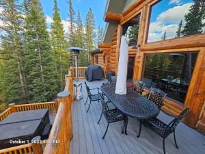 una terraza de madera con mesa y sillas en una cabaña en Moose Mtn Lodge/Luxury Cabin/Hot Tub/Fireplace, en Fairplay