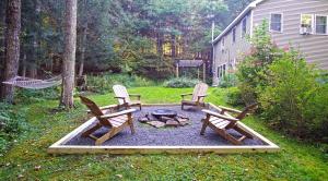un jardin avec trois chaises et un foyer extérieur dans l'établissement Secluded Streamside Home with Hot Tub, à Margaretville