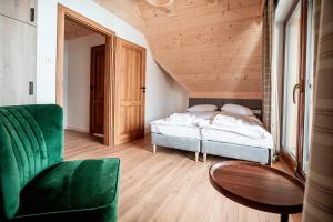 a bedroom with a bed and a green chair at Osada Widokówka- Przystanek Podhale in Czorsztyn