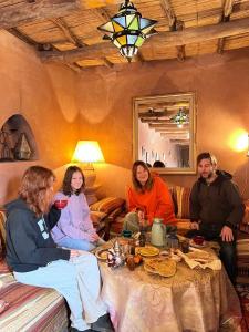 un grupo de personas sentadas alrededor de una mesa en Kasbah Tigmi El Janoub, en Aït Ben Haddou