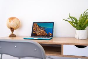 a laptop computer sitting on top of a wooden desk at STAYZED E - NG7 Free WiFi, Parking, Stylish House Near City Centre - Great For Tourists, Families, Contractors & Long Stays in Nottingham