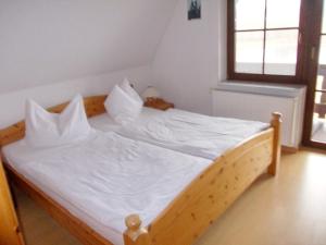 a wooden bed with white sheets and pillows on it at Finnhäuser am Vogelpark - Haus Anke in Marlow