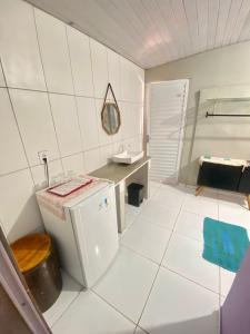 un bagno bianco con un piccolo frigorifero e un lavandino di Pousada Mar de vênus a Fernando de Noronha