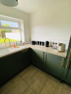a kitchen with green cabinets and a sink and a window at The Beautiful Bungalow Amazing location for Chester & Zoo in Wervin