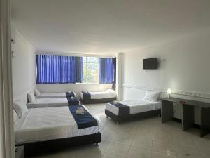 a hotel room with three beds and a television at SGH Castillo Aqua in Santa Marta +70 photos