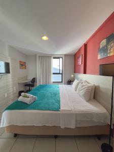 a bedroom with a large bed with a red wall at Janastí Suítes Praia de Ponta Negra in Natal