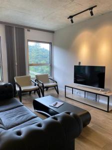 a living room with a couch and a flat screen tv at PRAIA BRAVA AP Mobiliado Condominio COMPLETO in Itajaí