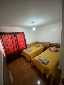 two beds in a room with a red curtain at Casa Quintero in Quintero