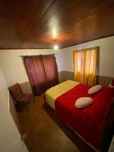 1 dormitorio con 1 cama roja y 1 silla en Casa Quintero, en Quintero