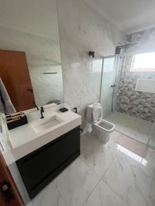 La salle de bains blanche est pourvue d'un lavabo et de toilettes. dans l'établissement Casa completa com piscina, 
