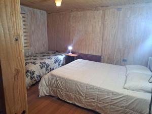 1 dormitorio con 2 camas y una lámpara en una mesa en Hostal Carhuello, en Pucón