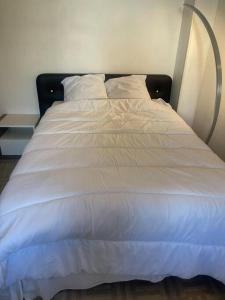 a white bed with a black headboard and white sheets at Appartement Croix rousse 69004 in Lyon