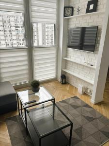 ein Wohnzimmer mit einem Couchtisch und 2 Fenstern in der Unterkunft Project Comfort Apartament Grzybowska 30/1211 in Warschau