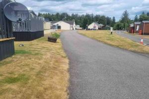 an empty road with a fence and a house at Coorie Nook, Chalet 103 in Aviemore