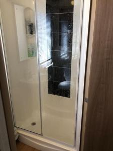 a shower with a glass door in a bathroom at Coorie Nook, Chalet 103 in Aviemore