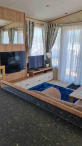 a living room with a flat screen tv and a room with at Coorie Nook, Chalet 103 in Aviemore