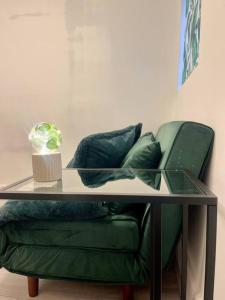 a green couch with a glass table in a room at Zen Garden Hideaway. Close to Harry Potter&trains. in Leavesden Green