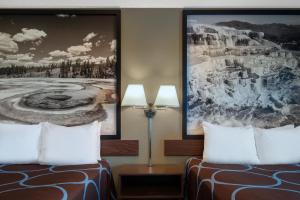 2 camas en una habitación de hotel con pinturas en la pared en Super 8 by Wyndham Livingston, en Livingston