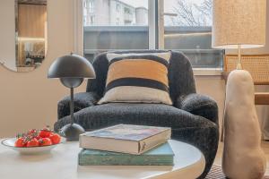 a living room with a chair and a table with books at Yuna Porte-Maillot - ApartHotel in Paris