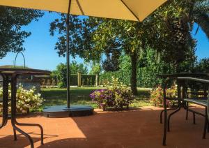 un patio con 2 mesas y una sombrilla en Il Casale Relais en San Giuliano Terme